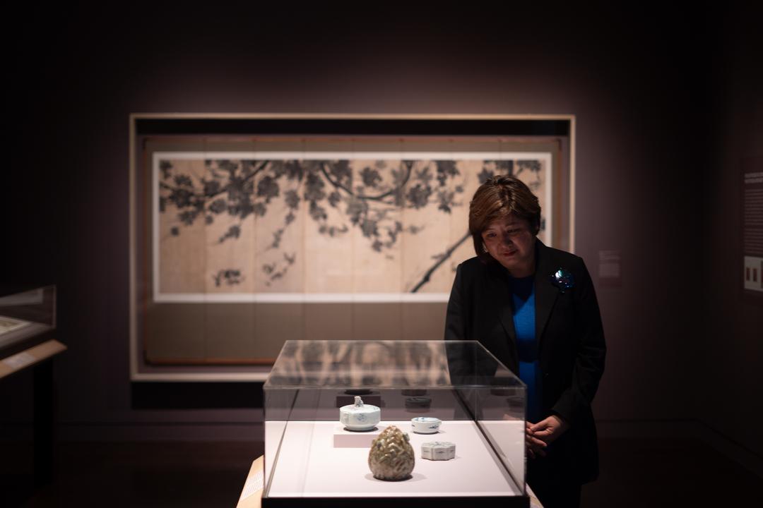 A woman looks into a glass vitrine of ceramic artworks