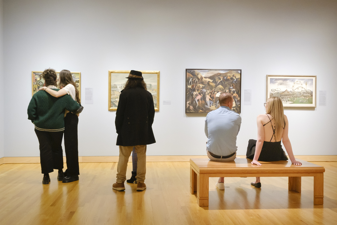 Several individuals stand in front of different artworks.