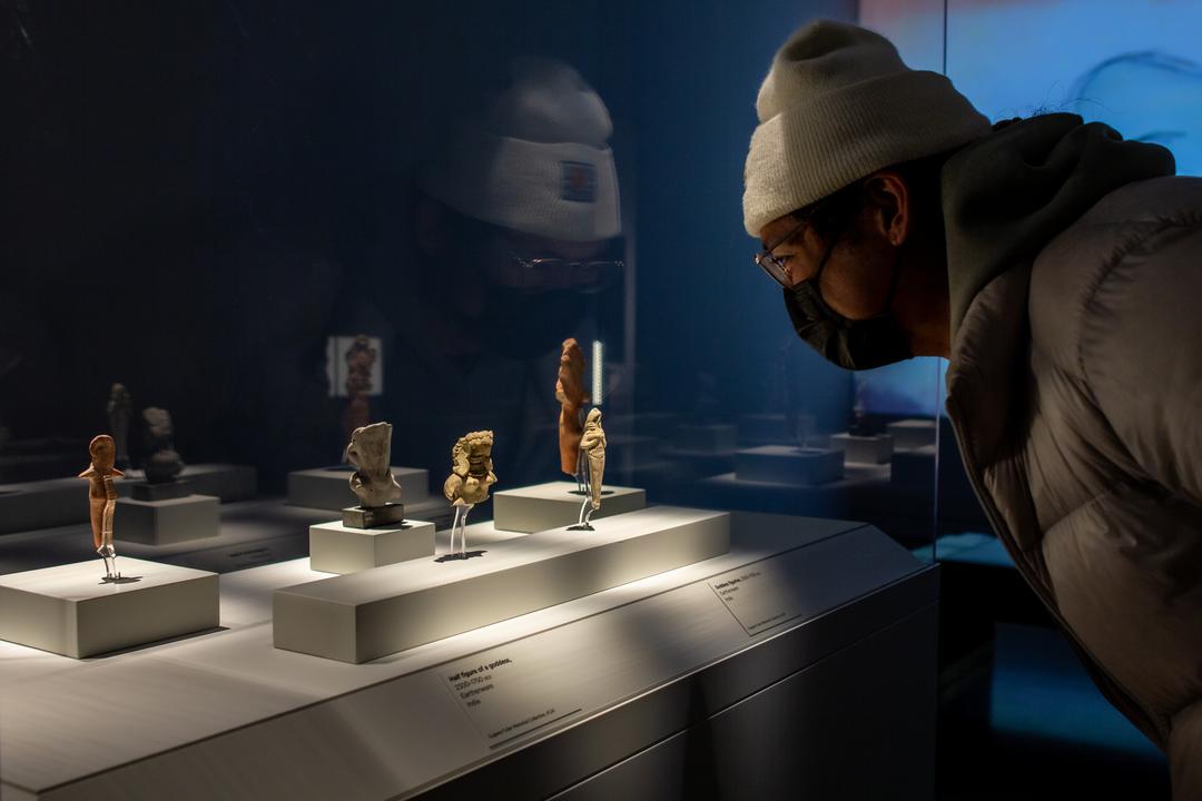 A person looking into a case filled with small sculptures